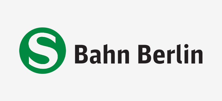 Im Logo der S-Bahn Berlin ist ein weisses „S“ in einem grünen Kreis zu sehen. Rechts daneben steht „Bahn Berlin“ in schwarzer Schrift auf weissem Hintergrund.